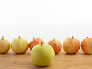Fresh red apples on a wooden table with a white background.