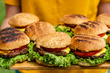 Closeup of homemade burgers made from fresh vegetables on wood plate holding women