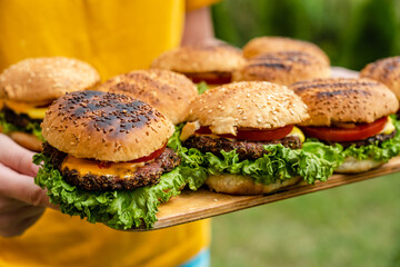 Closeup of homemade burgers made from fresh vegetables on wood plate holding women