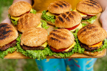 Closeup of homemade burgers made from fresh vegetables on wood plate holding women