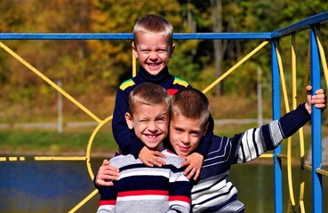 Obraz premium three cute brothers smiling and looking at the camera on the lake in the park