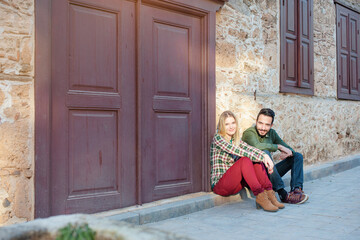 multi ethnic couple sitting on the ground in city