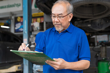 Senior asian man mechanic worker maintenance car engine under hood of car at automotive motor garage