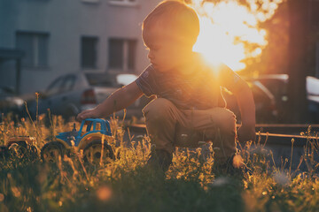 Child playing with toys outside. Little boy having fun on playground in sunset. Outdoor creative activities for kids. Summer and childhood concept
