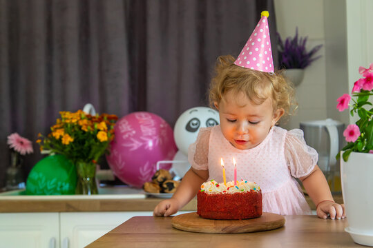 Child is two years old with a cake and candles. Selective focus.