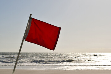 red hazard flag on beach indicates danger of high surf and wind