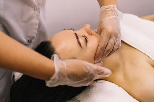 Woman receiving facial buccal massage in beauty salon.Beauty and skincare concept with a beautiful woman. Middle aged female relaxed with massage for facial lifting