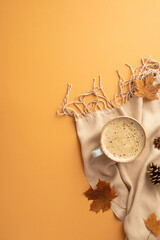 Hello autumn concept. Top view vertical photo of cup of frothy hot drinking anise yellow maple leaves pine cones and plaid on isolated orange background