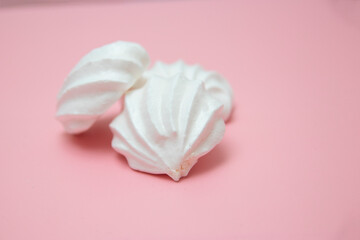 White meringues on pink background. French dessert prepared from whipped with sugar and baked egg whites. Greeting card with copy space