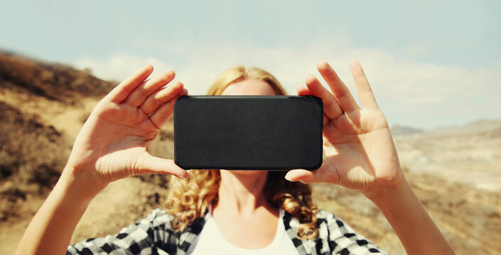 Close up woman stretching her hands for taking selfie picture by smartphone on a hiking trail on top of the mountain, Tenerife, Canary Islands, Spain