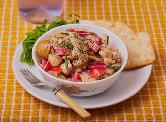 Chicken and potato sald in a white bowl with crackers.