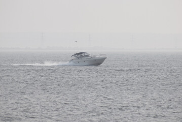 A modern marine Motor yacht rushing through the waves on the shore of the bay. Travel and vacation concept. Black and white photography