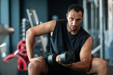 Portrait Of African American Male Athlete Training With Dumbbell At Gym