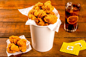 Crispy Boneless chicken wings Bites 12 piece with drink and ketchup served in a basket isolated on wooden board on grey background side view of fastfood