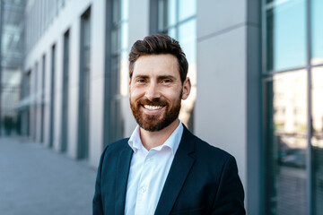 Portrait of smiling confident attractive millennial businessman with beard in suit looking at camera