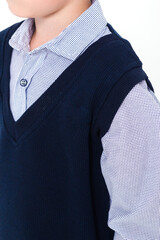 The boy poses in a school uniform - a shirt and a sleeveless jacket on a white background