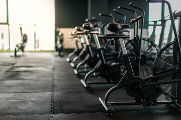 Fototapeta na wymiar Fitness Equipment. Stationary Bikes Standing In A Row At Empty Gym