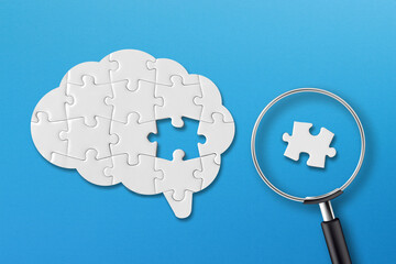 Brain shaped white jigsaw puzzle on blue background. Searching missing piece of the brain puzzle...