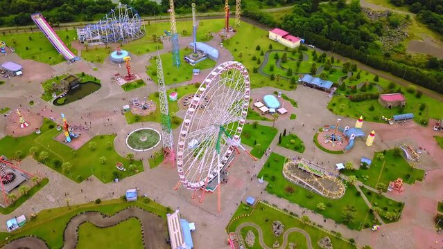 Top view of amusement park with Ferris wheel and roller coaster at sunset in Georgia at Tsitsinatela Park. Ferris wheel with air illumination. Recreation area of Georgian park on Black Sea coast.