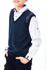 The boy poses in a school uniform on a white background. The teenager is wearing a shirt, vest and trousers