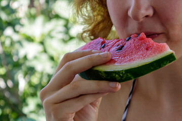 Close-up of hand of young woman holding and eating watermelon 