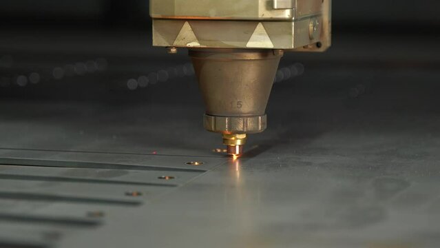 Close-up CNC laser cutting machine. 
The metal sheet is cut on the cnc machine and holes are drilled on it. Laser cutting device following laser light and laser light.  Cutting of industrial metal par