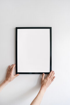 Woman hand install copy space picture frame on wall