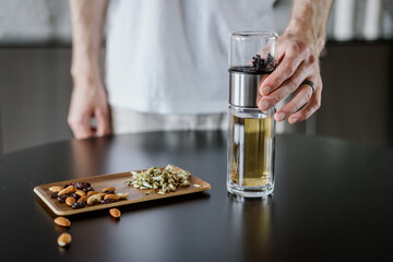 man brewing herbal tea in infuser or glass travel bottle