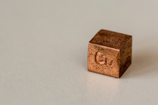 Copper cube with element name Cu on it on cream background