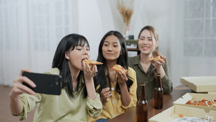 Holiday concept of 4k Resolution. Group of Asian female friends inviting online friends to eat pizza together at home. Fun and exciting leisure activities.