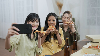 Holiday concept of 4k Resolution. Group of Asian female friends inviting online friends to eat pizza together at home. Fun and exciting leisure activities.