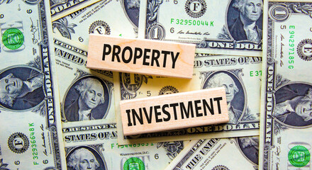 Property investment symbol. Concept words Property investment on wooden blocks on a beautiful background from dollar bills. Business Property investment concept. Copy space.