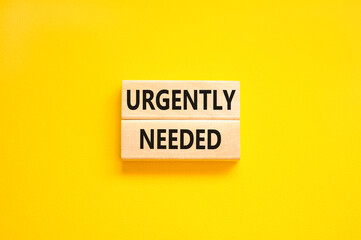 Urgently needed symbol. Concept words Urgently needed on wooden blocks on a beautiful yellow table yellow background. Business and urgently needed concept. Copy space.