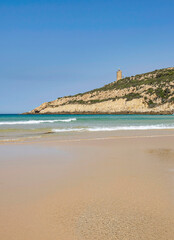 Ca?uelo beach in Spain. Orange beach without people, turquoise water and in the background a mountain with a lighthouse. Blue sky. Peace, tranquility.