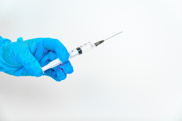 women's hands in blue gloves with a disposable syringe. 