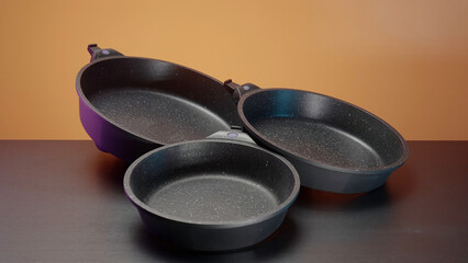 Concept of kitchen utensils, close up of new set of frying pans lying on the table. Action. New...