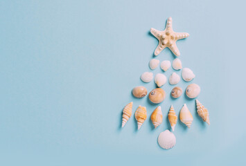 Christmas tree from sea shells, starfish alternative decoration blue background, new year by sea