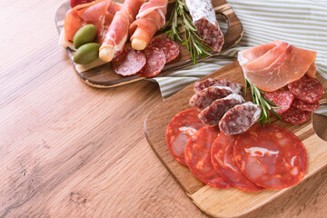 Appetizer plate, charcuterie plate with different types of sausages - salami, bresaola, proscuitto served with grissini bread sticks. Menu background. Traditional italian antipasti at wooden table