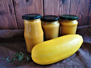 Vegetarianism. A yellow squash and three cans of squash caviar are on the brown table. Cooking. Vegetarian, natural products. Healthy lifestyle.