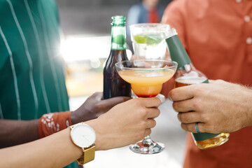 Close up of friends clinking various alcohol glasses while enjoying outdoor party