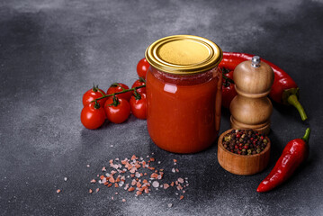 Spicy sweet tomato sauce with garlic, pepper and herbs in a glass jars