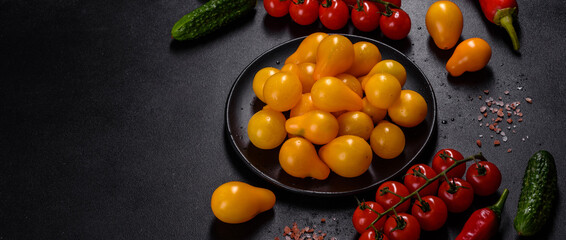 Fototapeta na wymiar Pear-shaped small yellow tomatoes in a ceramic plate on a dark concrete table