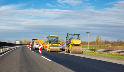 Road works on highway. Asphalt rollers and other equipment.
