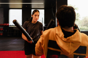 Fototapeta na wymiar female boxing coach training a boy in gym