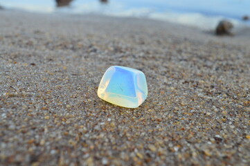 Fototapeta na wymiar Opalite mineral on sand background 
