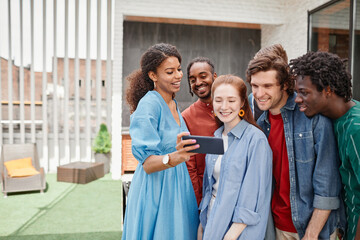 Portrait of diverse group of friends taking selfie photo at outdoor party or speaking by video chat, copy space
