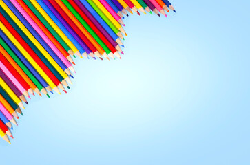 multicolored pencils lie in a row in the corner on a blue background, the concept of the school. High quality photo