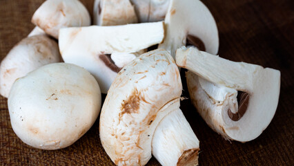 White mushrooms, chopped up in bite size pieces and bundled together on a dark brown chopping board.
Kitchen inspiration and food preparation concept.
