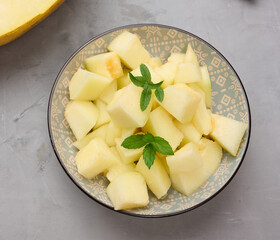 Sliced pieces of melon in a round gray plate on the table