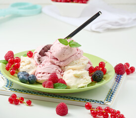 Vanilla and raspberry ice cream scoops on a round green plate